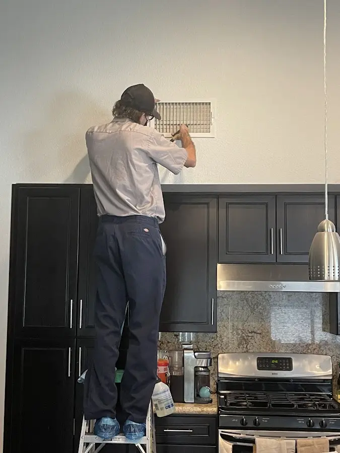 Technician inspecting an air vent during HVAC service in Mill Creek East